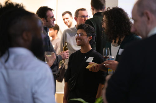 Un groupe de personne de tous âges et origines discutent en souriant et en prenant l'apéro